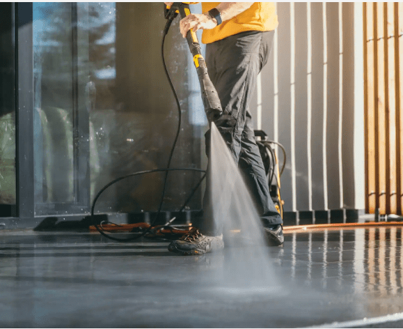 Man using power washer on patio