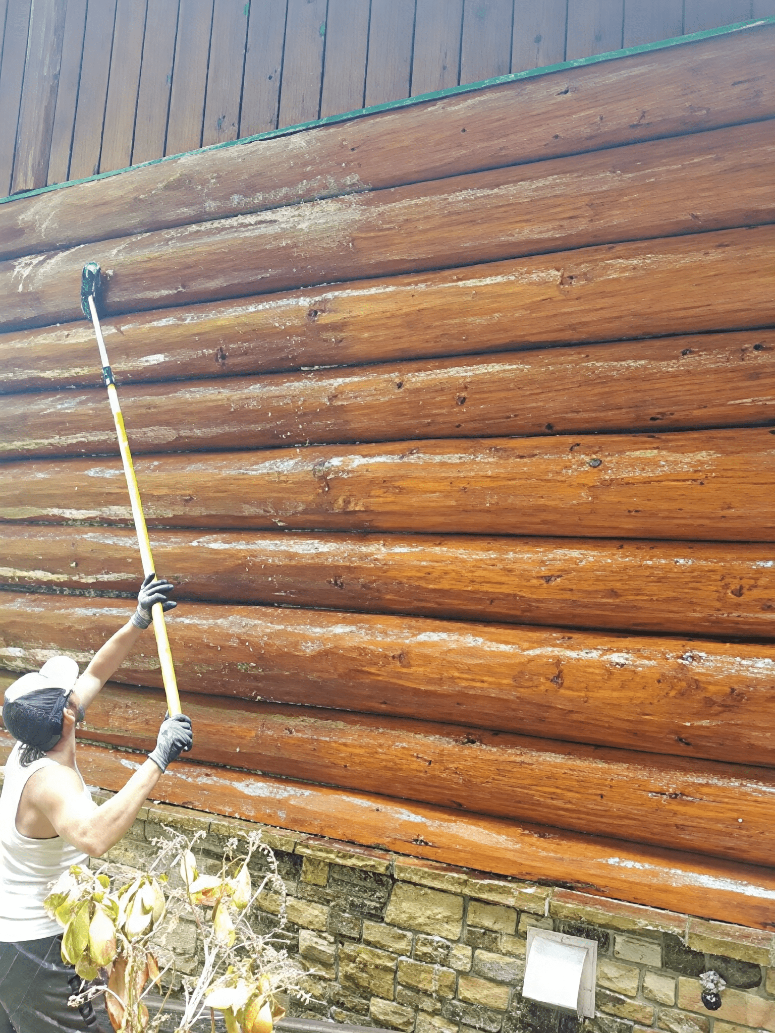 Maintaining wooden cabin with a cleaning tool.