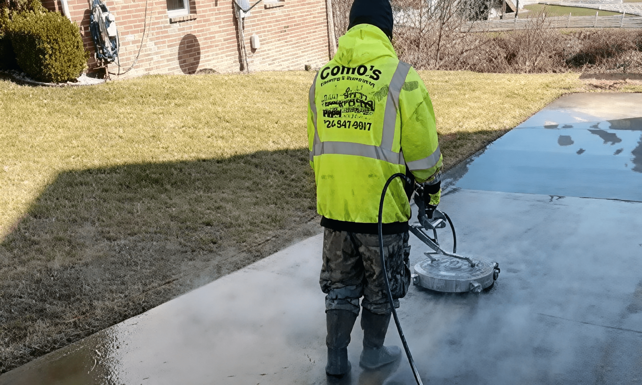 Worker pressure washing a driveway