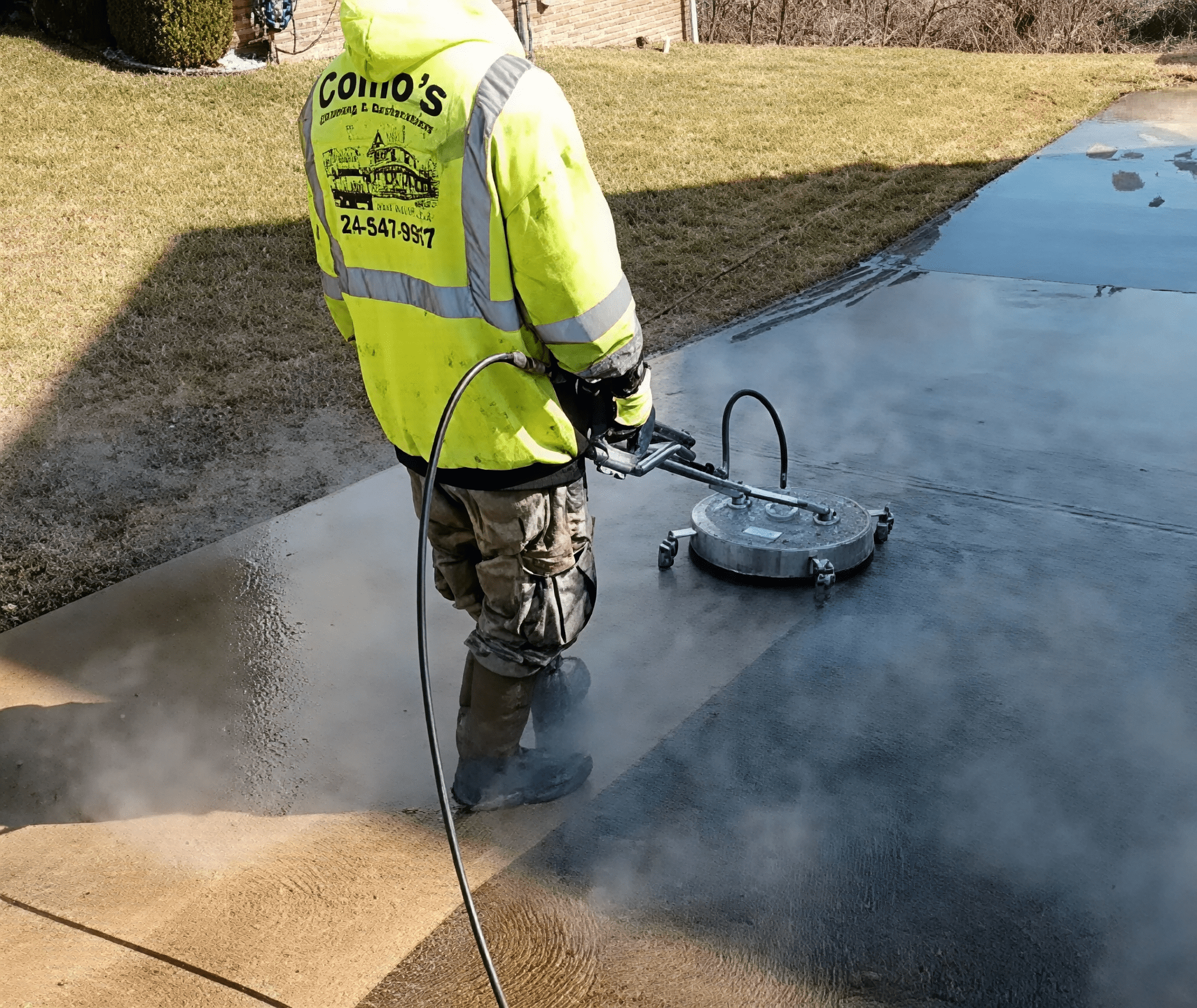 Worker pressure washing a driveway