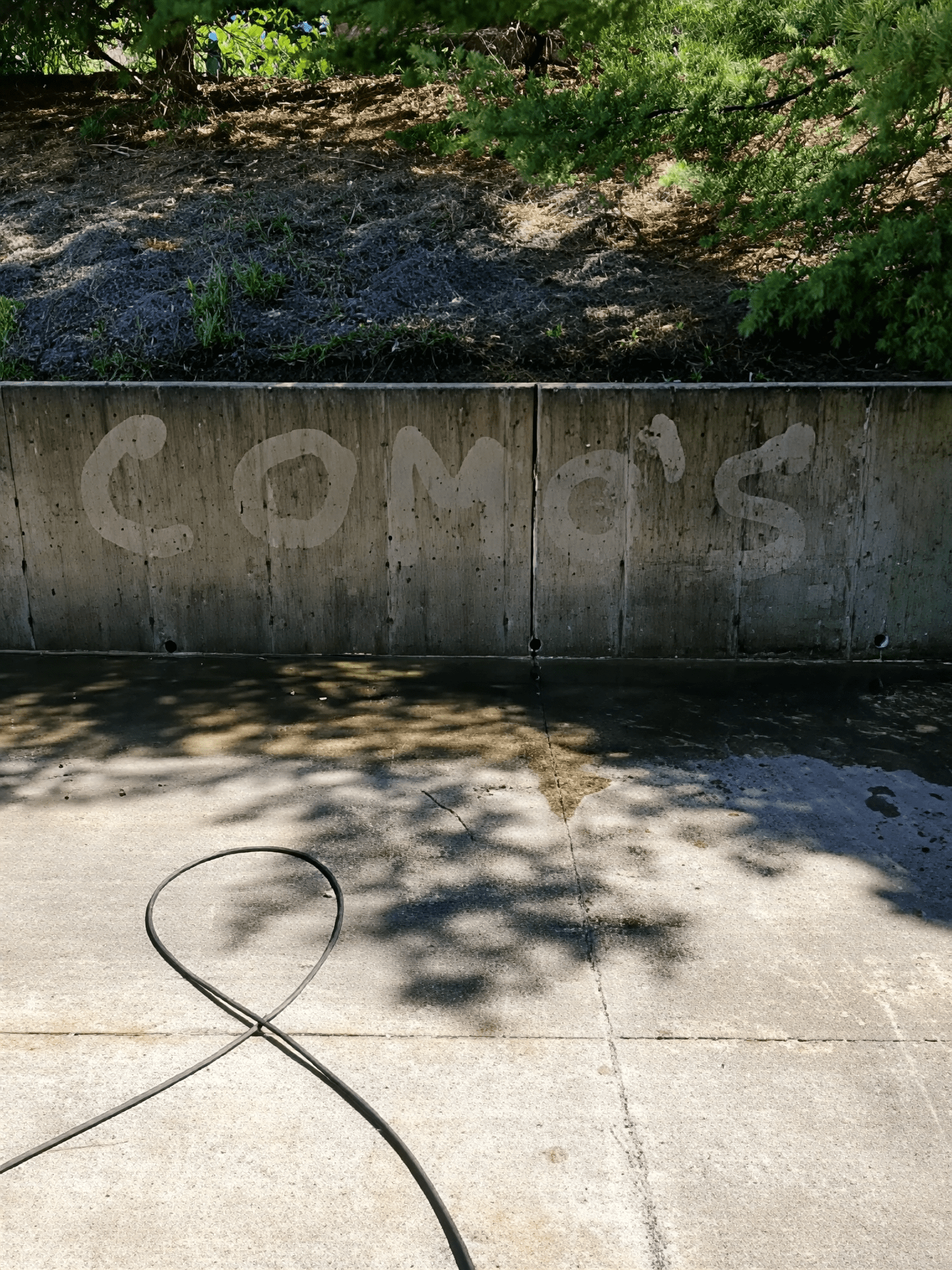 Concrete wall with "COMO'S" washed graffiti