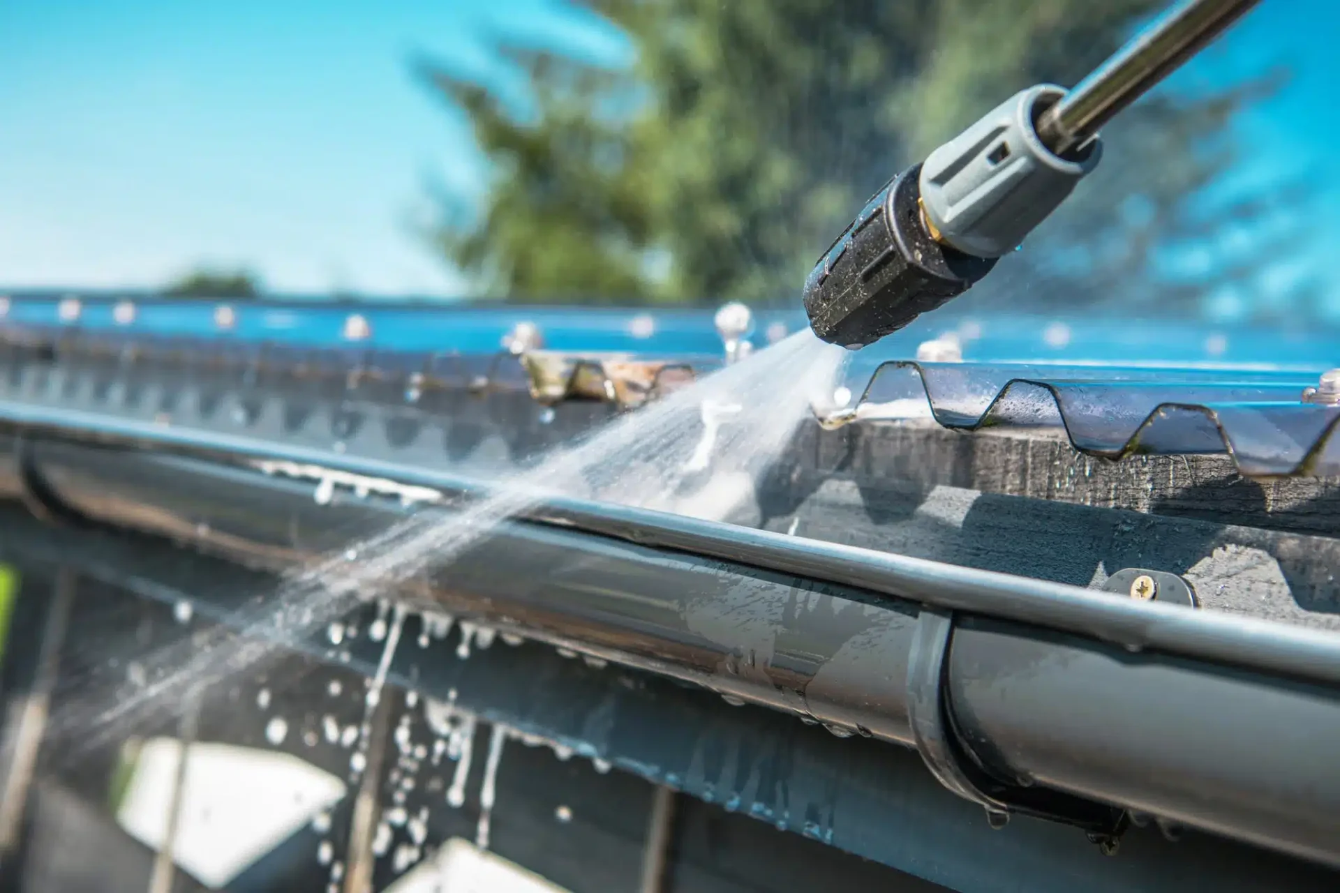 Pressure washing a roof gutter